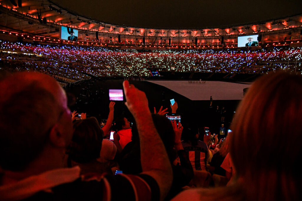 Personas en primer plano con celulares en alto, y miles más en el fondo iluminando el estadio Maracaná durante la inauguración de los Juegos Paralímpicos de Río 2016.