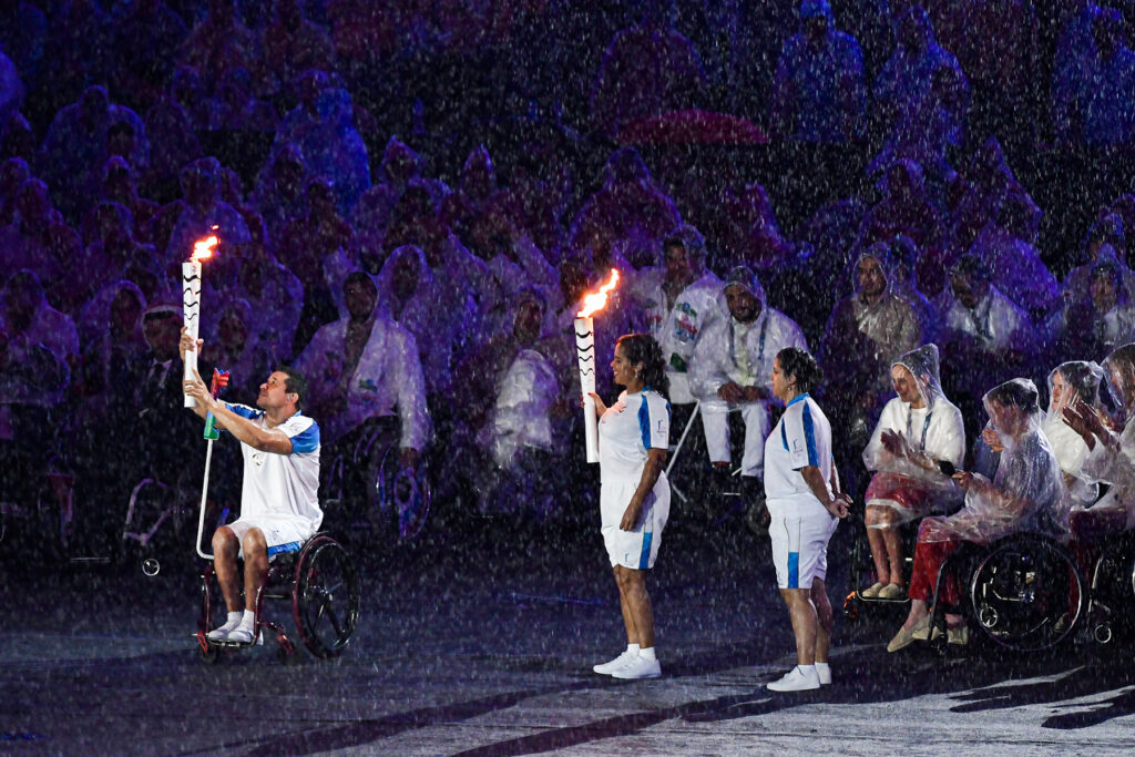 Deportistas sostienen la antorcha paralímpica bajo una lluvia artificial durante la ceremonia de apertura de los Juegos Paralímpicos de Río 2016.