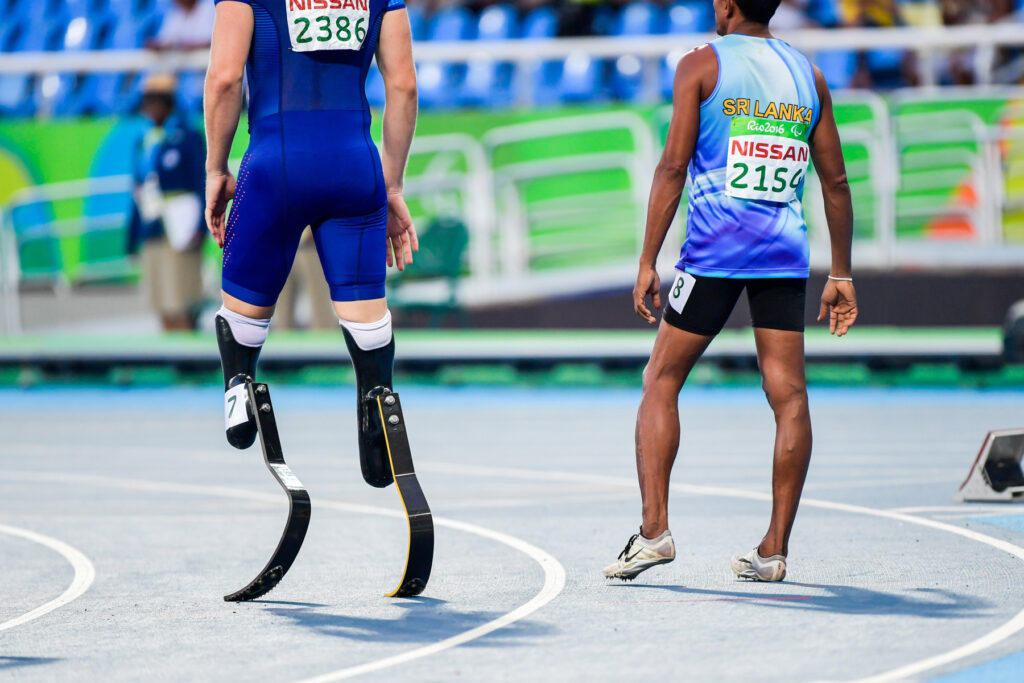 Dos atletas compiten en relevos en una prueba de atletismo, uno de ellos utilizando prótesis en sus piernas.