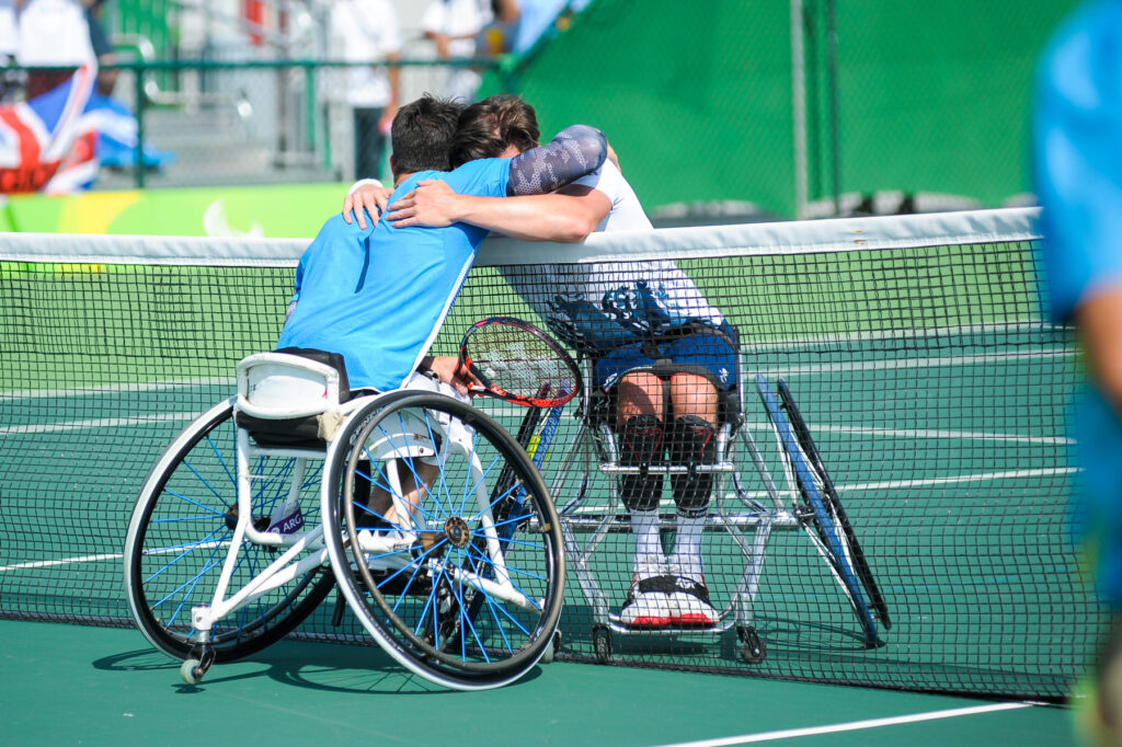 Gustavo Fernández y Reid Gordon se abrazan a través de la red al finalizar su partido en el tenis en silla de ruedas.