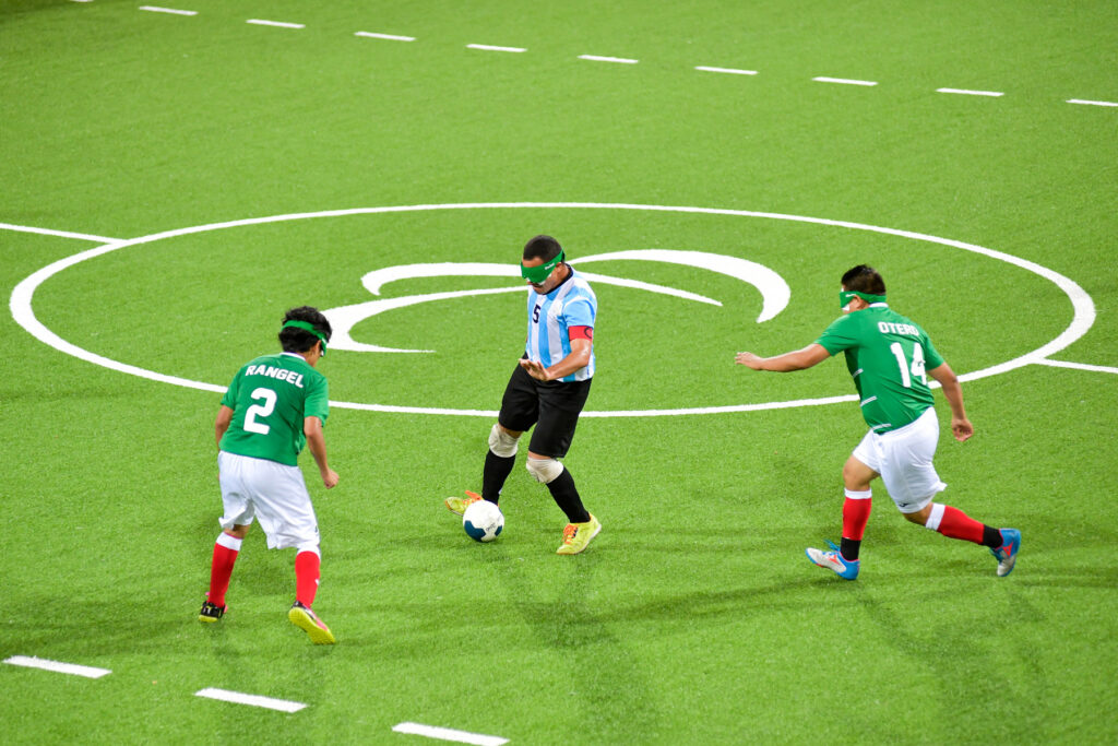 Silvio Velo, capitán de la Selección Argentina de fútbol para ciegos, en el centro de la cancha con dos jugadores iraníes a su lado.