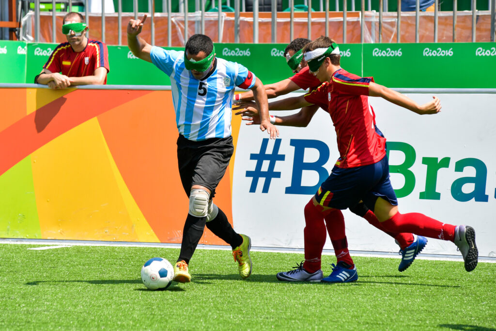 Silvio Velo, capitán de la Selección Argentina de fútbol para ciegos, esquiva a dos españoles con la pelota en sus pies.